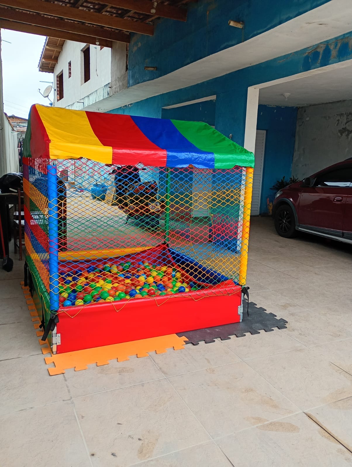 Piscina de bolinhas com cobertura colorida e rede de proteção montada pela JD Kids