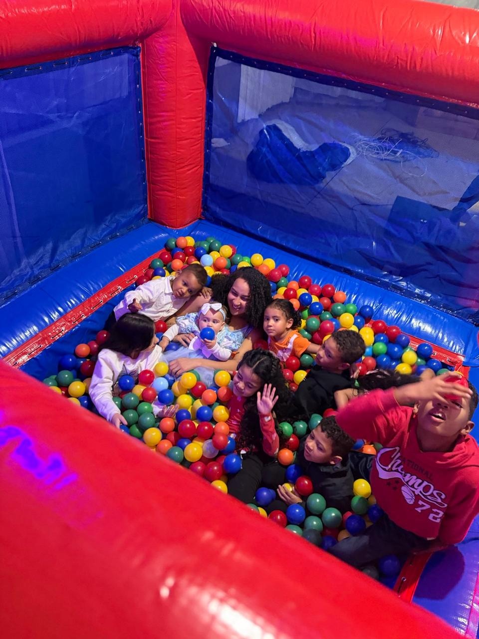 Crianças brincando com bolinhas coloridas na piscina inflável vermelha e azul da JD Kids
